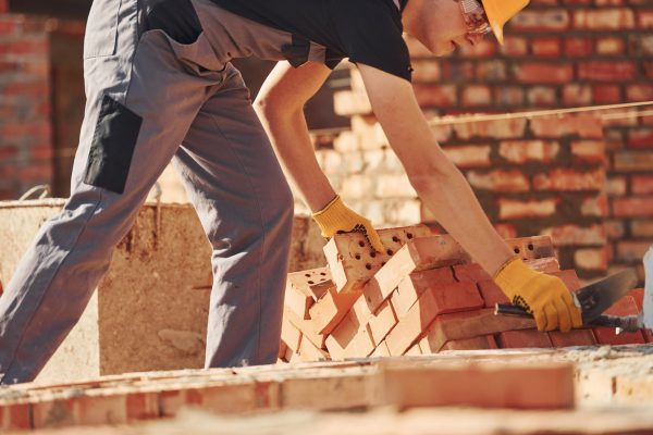 Construction worker in uniform and safety equipment have job on building.